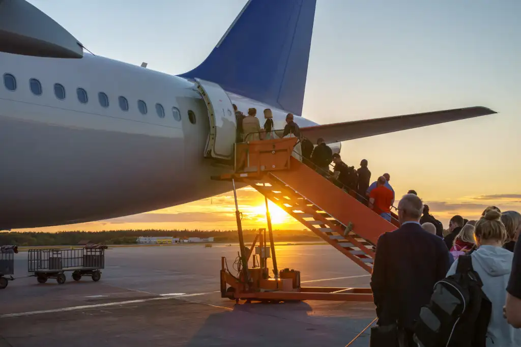 People boarding airplane from runway using stairs