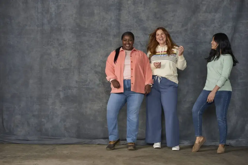 Three women standing against a grey wall, dressed in clothing from L.L. Bean