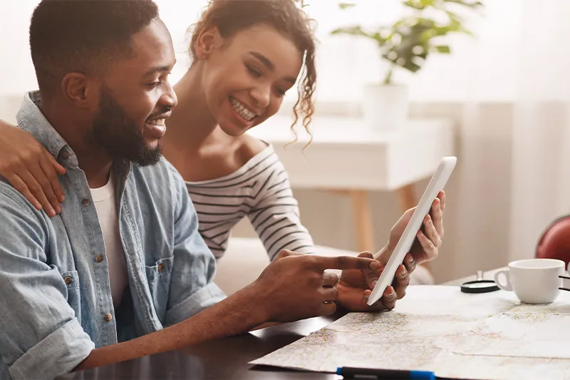 Couple planning a trip with a map and a tablet