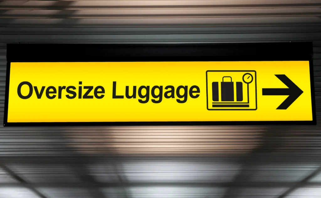 oversize luggage yellow sign with arrow direction hang from ceiling at the airport