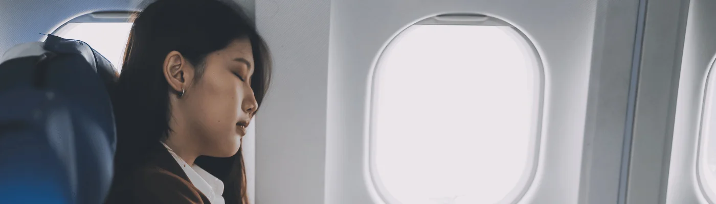 Photo of woman sitting on an airplane trying to sleep