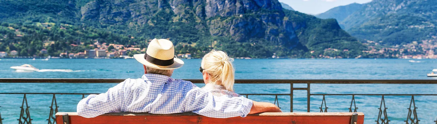 Senior couple sitting on bench enjoying a waterfront view in Italy
