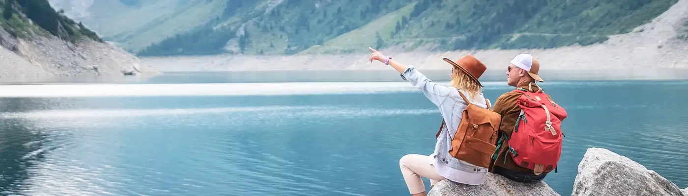 Travelers couple look at the mountain lake. Travel and active life concept with team. Adventure and travel in the mountains region in the Austria