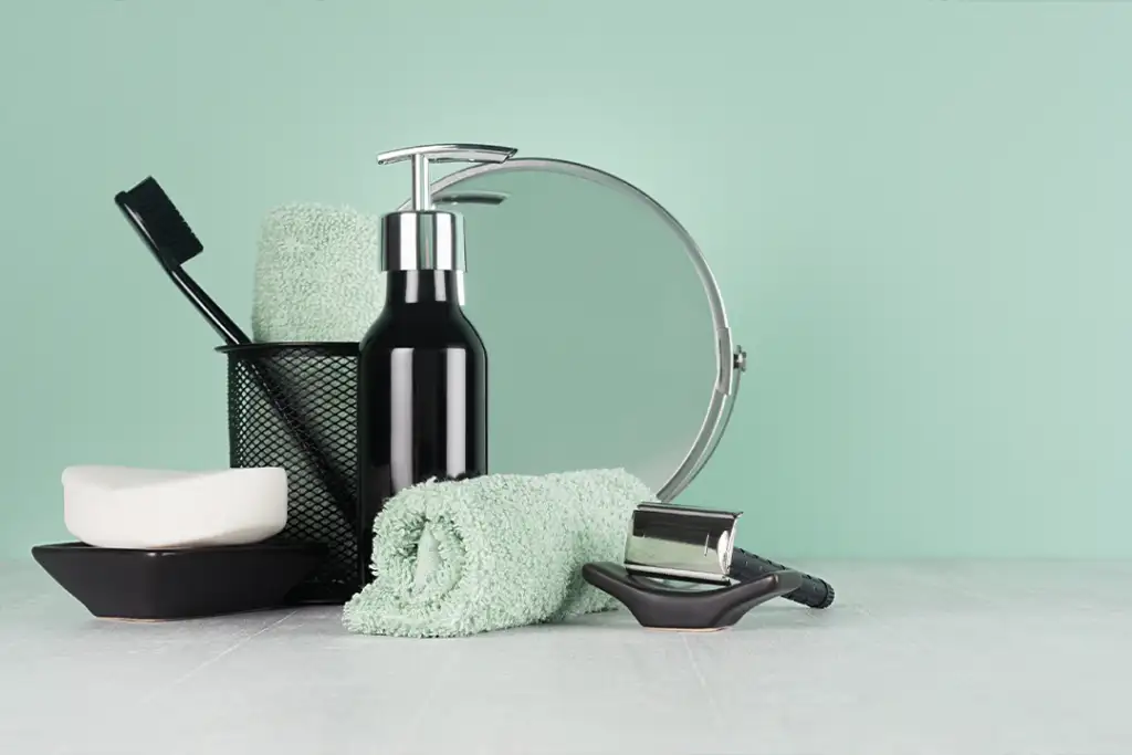 Elegant men dressing table in trend green mint menthe color - black razor, toothbrush, mirror, soap, towel, dispenser on light white wood table.
