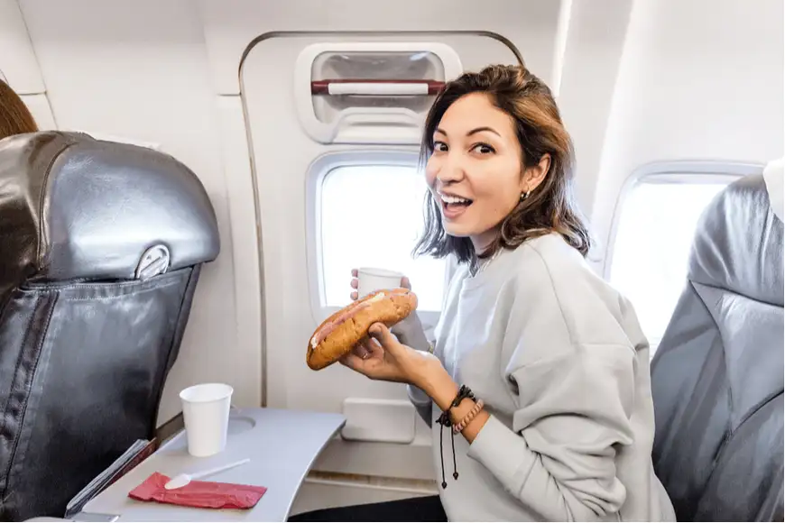 woman eating sandwich on plane.
